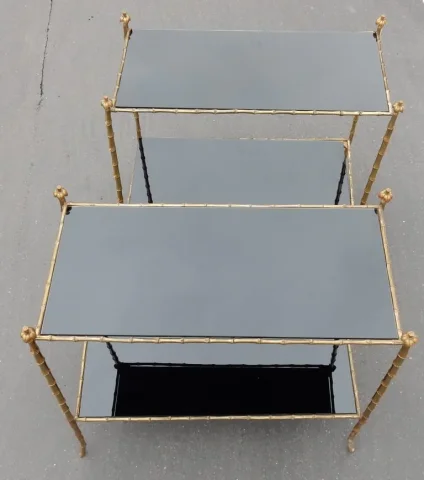 Paire de tables en bronze doré, plateaux en verre laqué noir, décor palmier avec cimes en haut des montants  Tout est vissé Bon état Circa 1950/70  Longueur : 74 cm Largeur : 38 cm Hauteur : 68 cm