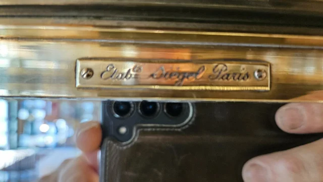 SIEGEL : Rare vitrine murale d’exposition en laiton et bronze à cotés bombés. Début du XX° siècle. — Excellent état