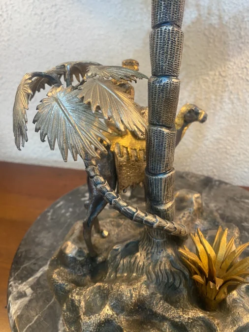 Sculpture en métal figurant un chamelier dans une oasis