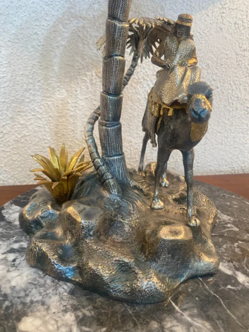Sculpture en métal figurant un chamelier dans une oasis