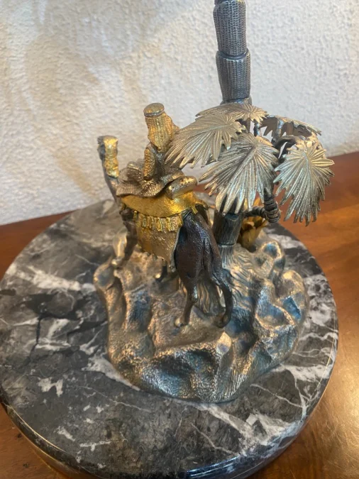 Sculpture en métal figurant un chamelier dans une oasis