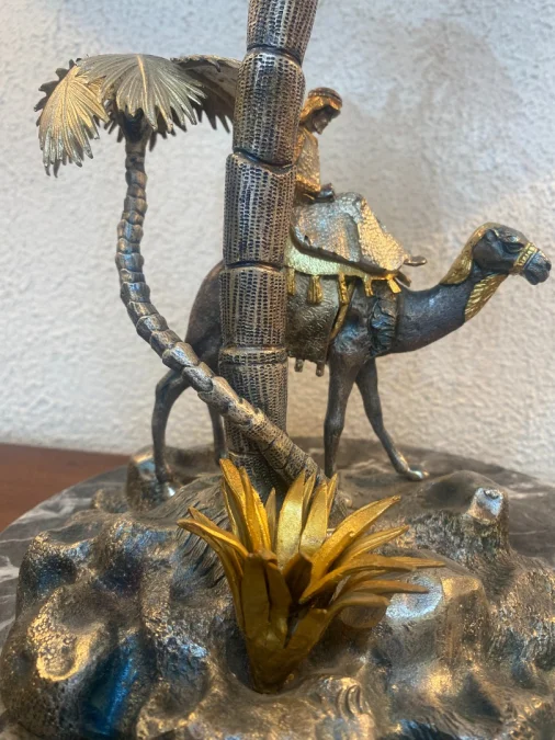 Sculpture en métal figurant un chamelier dans une oasis