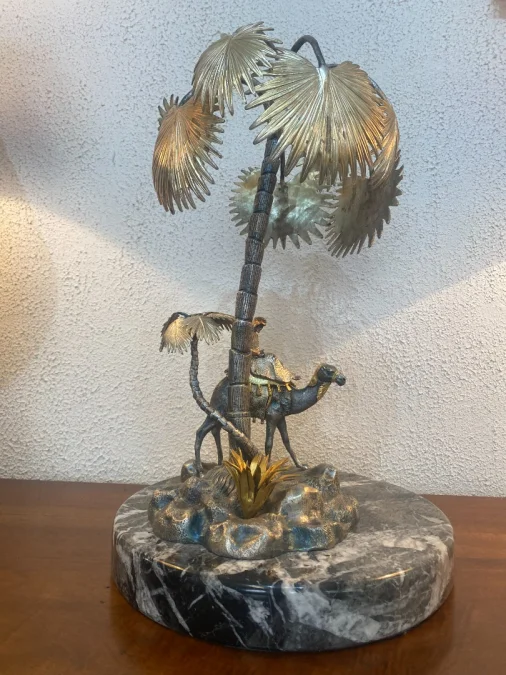 Sculpture en métal figurant un chamelier dans une oasis