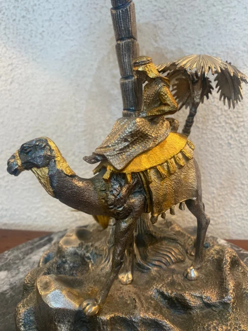 Sculpture en métal figurant un chamelier dans une oasis