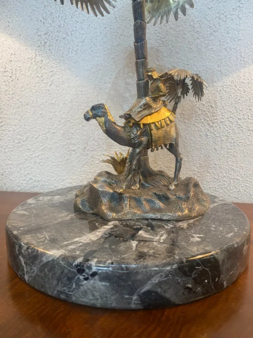 Sculpture en métal figurant un chamelier dans une oasis