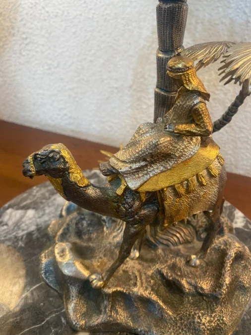 Sculpture en métal figurant un chamelier dans une oasis