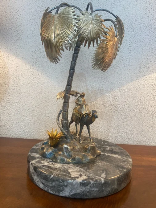 Sculpture en métal figurant un chamelier dans une oasis