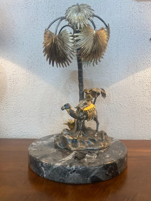 Sculpture en métal figurant un chamelier dans une oasis